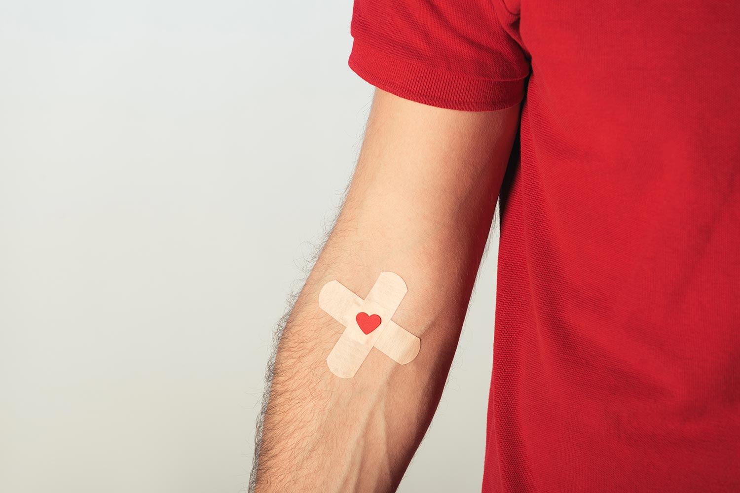 partial-view-patient-red-t-shirt-with-plasters-grey-background-blood-donation-concept